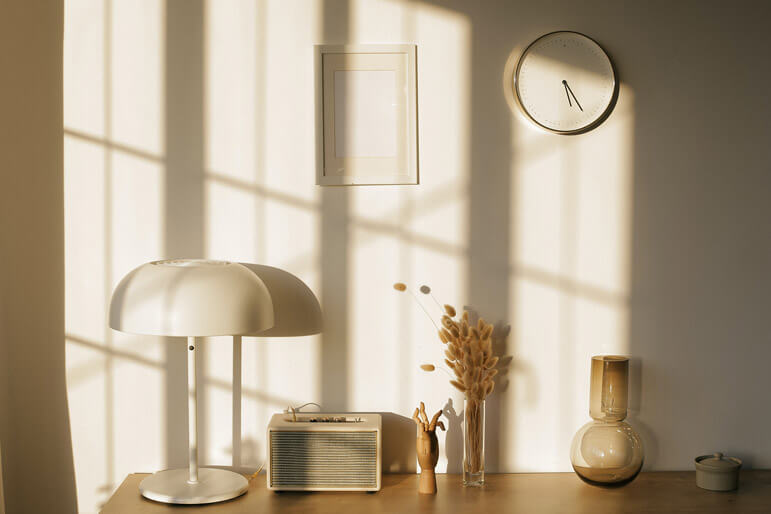 The sun shines through an office window with grilles causing a rectangular light pattern on the desk items.